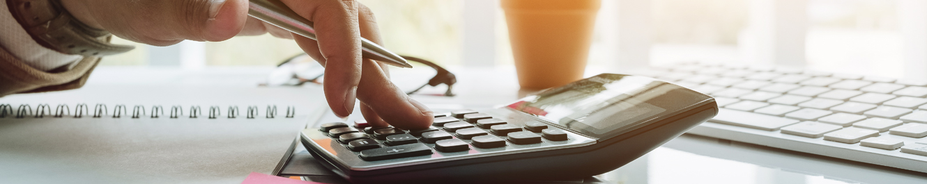 fingers holding a pen and using a calculator