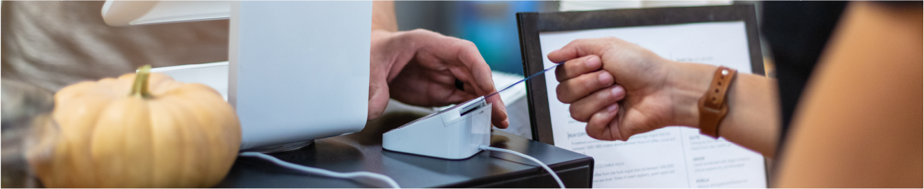 one hand holds a credit or debit card reader while the woman making a purchase dips her chip-enabled card into the reader