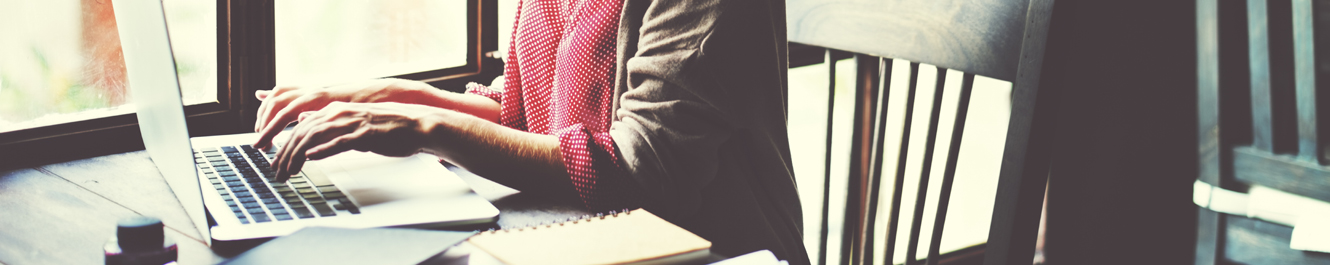 woman sits at a table typing on her laptop